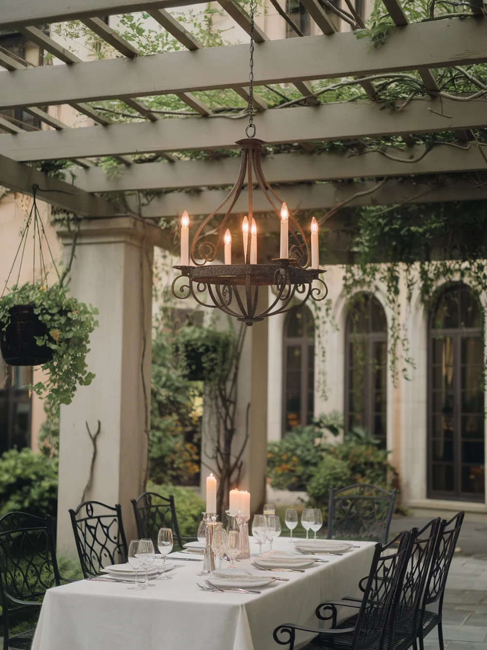 A candle-style outdoor chandelier hanging above a beautifully set dining table in a garden.
