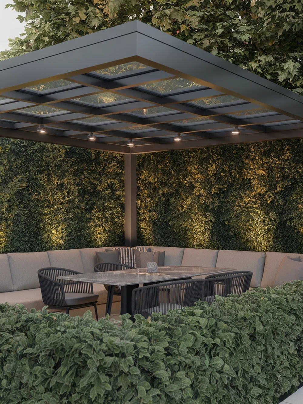 A modern glass roof pergola with cozy seating and surrounding greenery.